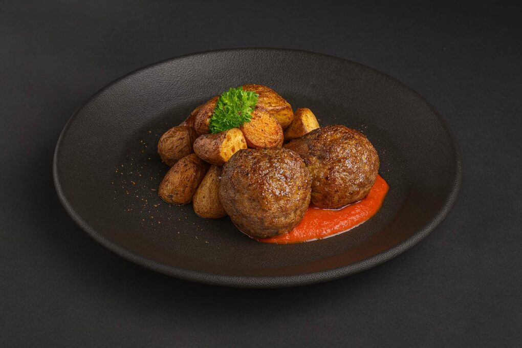 Zwei Fleischbällchen mit gerösteten Kartoffeln und Paprikacreme